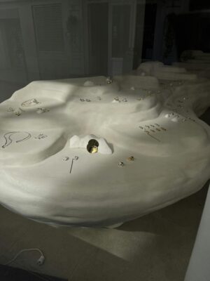 A modern jewelry display with gold and silver pieces on a unique white abstract surface.