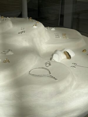 Aesthetic display of gold and silver jewelry on a smooth white surface.