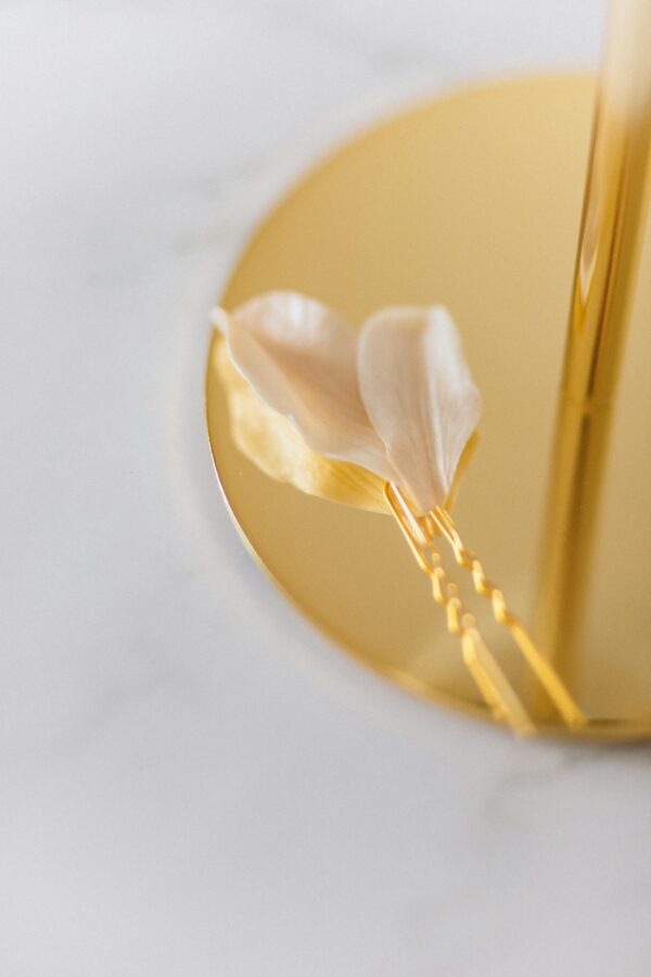 Close-up of a sophisticated gold hairpin with delicate floral accents on a marble surface for a stylish look.
